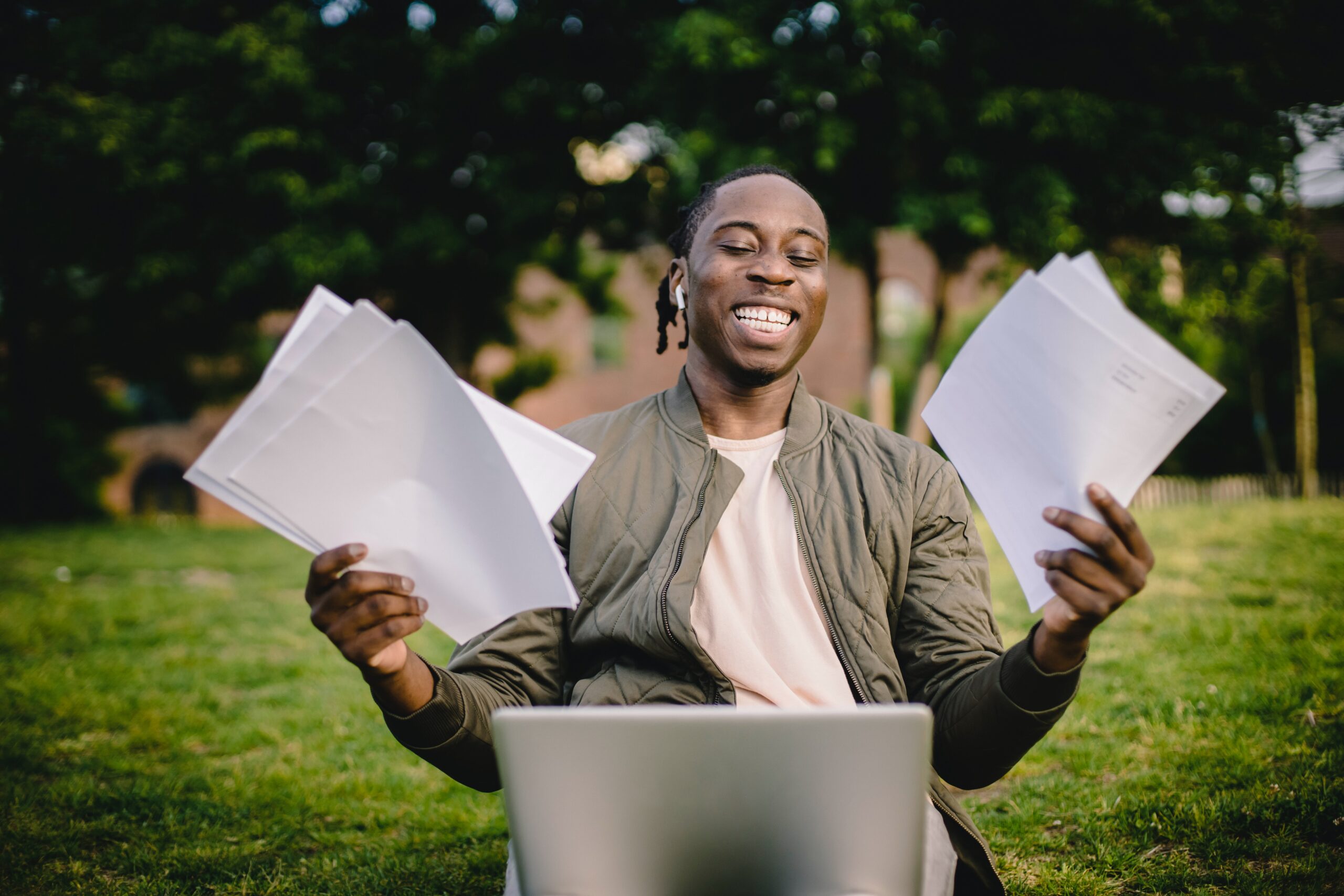 homem sorridente segurando folhas em frente ao computador