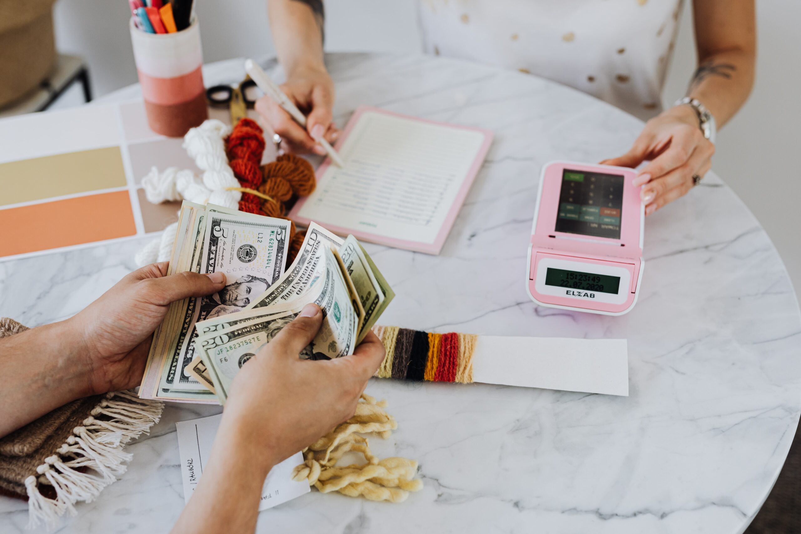 Pessoas em uma mesa fazendo cálculos e contando dinheiro