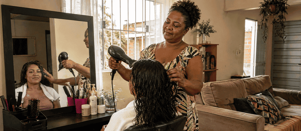 Cabeleireira trabalhando por conta própria no salão montado em casa, exemplo de como empreender com pouco dinheiro